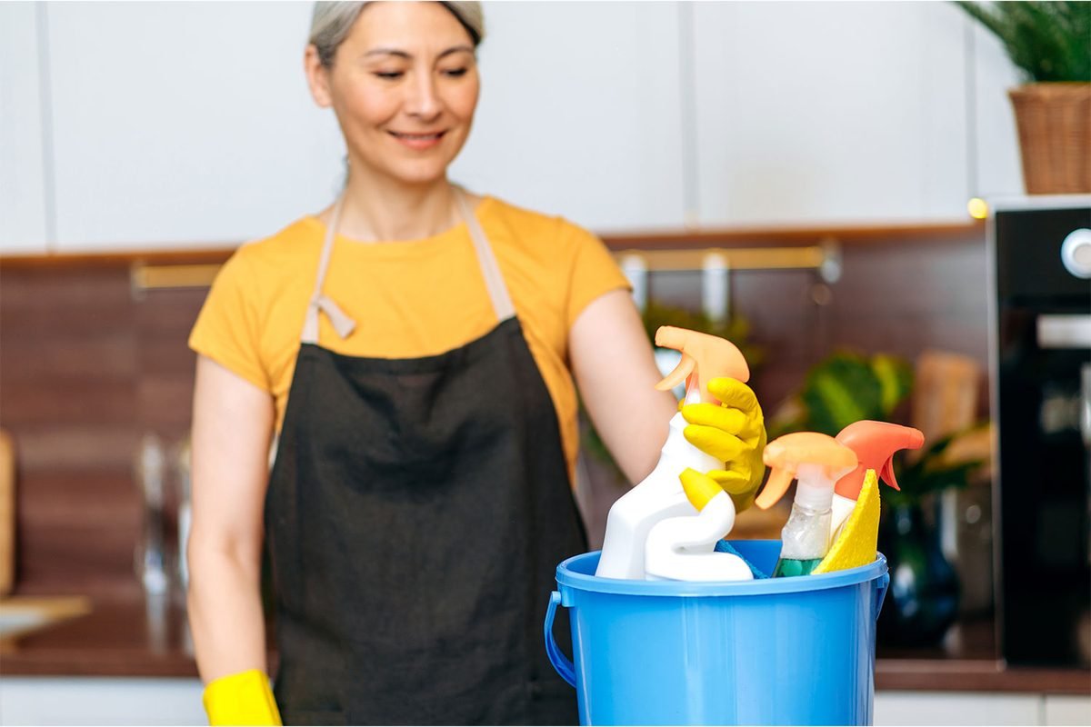 Cleaner carrying a caddy of cleaning supplies for a rental turnover
