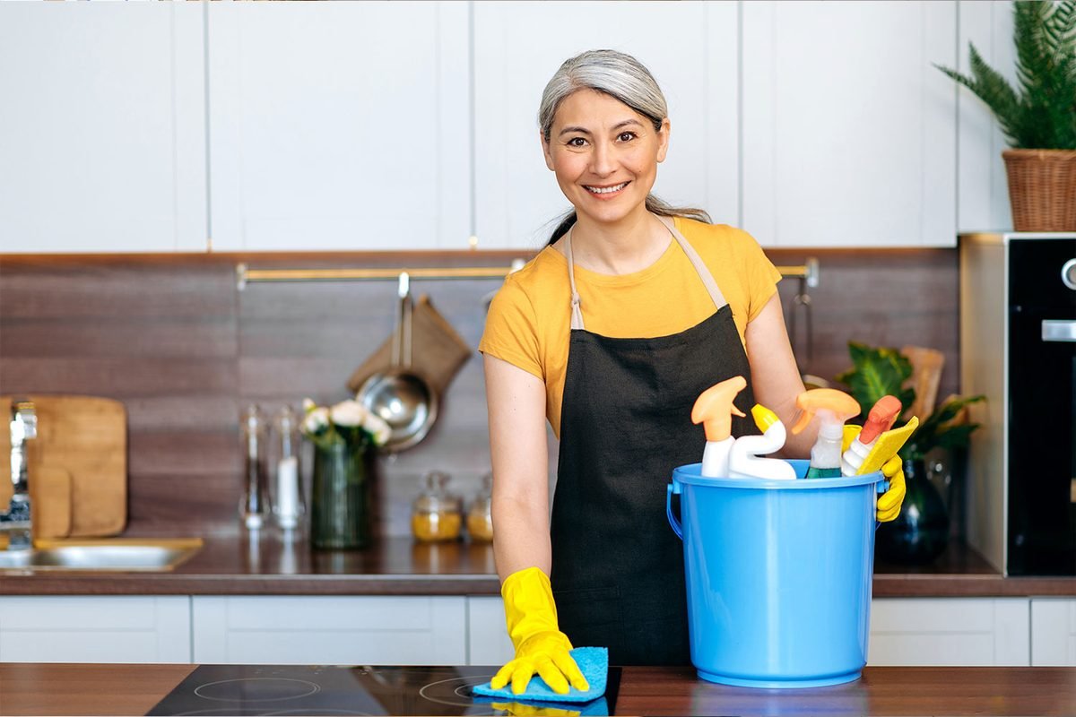 Cleaner wiping down a kitchen cooktop during a move-out clean